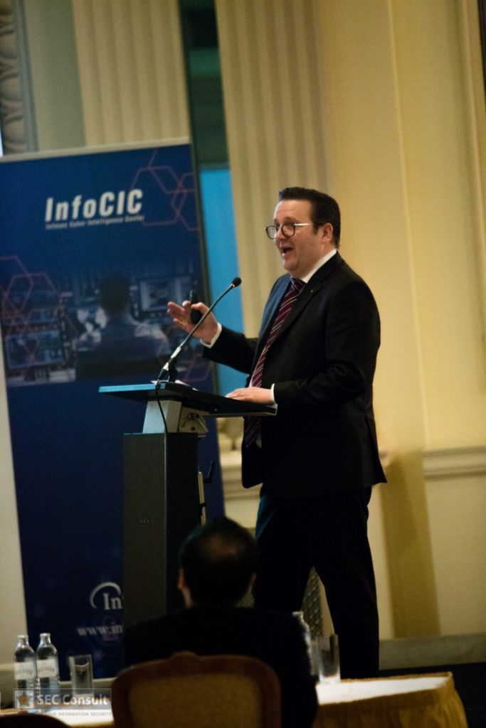 Man with glasses talking at the lectern - Global cybercrime